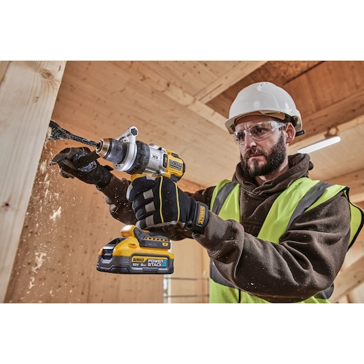 Construction worker using 18V XR Brushless Premium Hammer Drill Driver with 5Ah Powerstack to drill a hole in wood