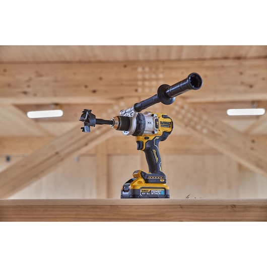 18V XR Brushless Premium Hammer Drill Driver with side handle and Powerstack 5Ah battery sitting on top of a wooden table