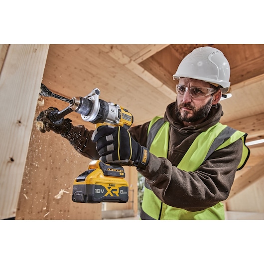 Construction worker using 18V XR Brushless Premium Hammer Drill Driver with 8Ah battery to drill a hole in wood