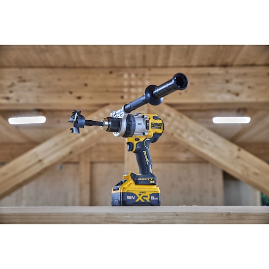 18V XR Brushless Premium Hammer Drill Driver with side handle and 8Ah battery sitting on top of a wooden table