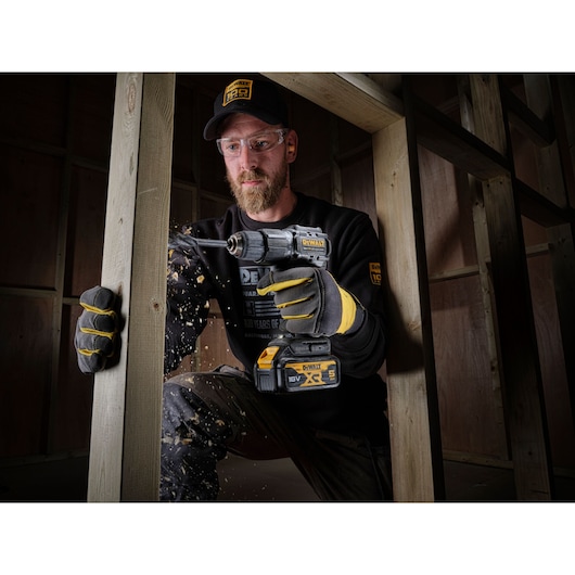 Worker in 100 years of DEWALT top drilling through timber stud wall