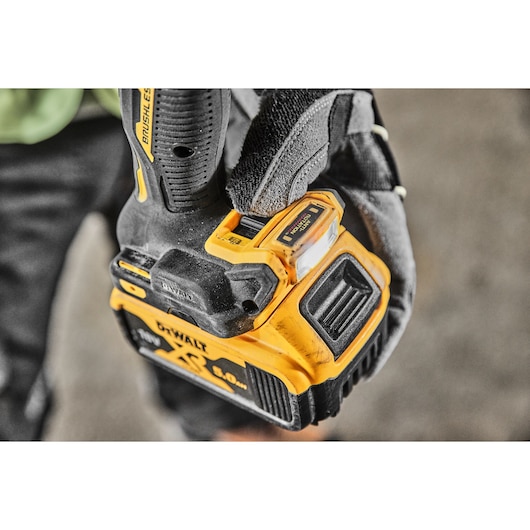 A gloved hand pushing the LED light switch on the base of the DCD800P2T 18V XR Brushless Drill Driver 