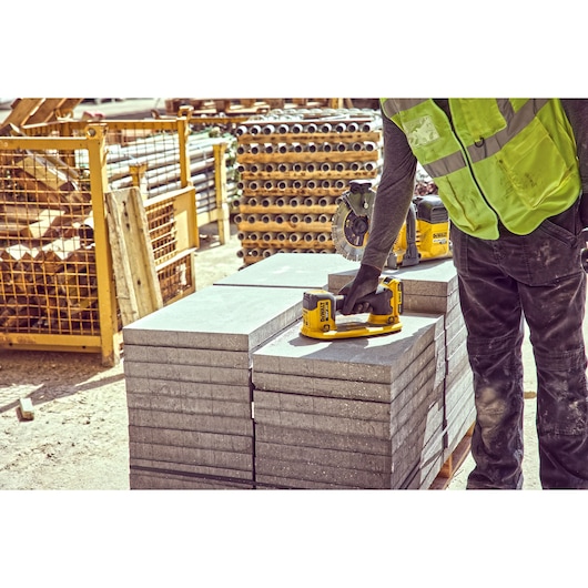 Construction worker holds a Grabo 18V XR Suction Lifter on top of a column of concrete blocks