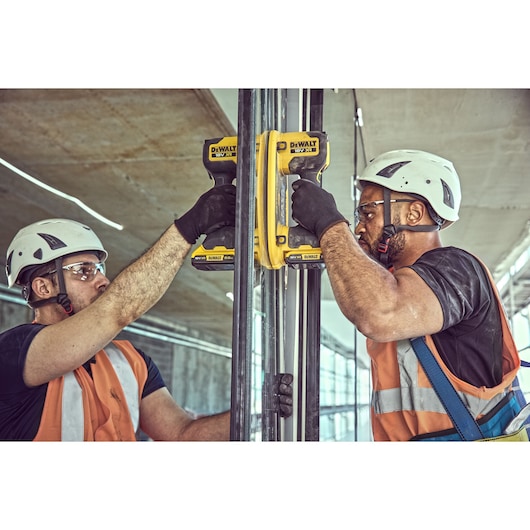 Two construction workers each attach a Grabo 18V XR Suction Lifter to a large pane of glass