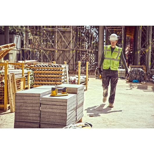 Construction worker walks towards a column of concrete blocks on which sits a Grabo 18V XR Suction Lifter