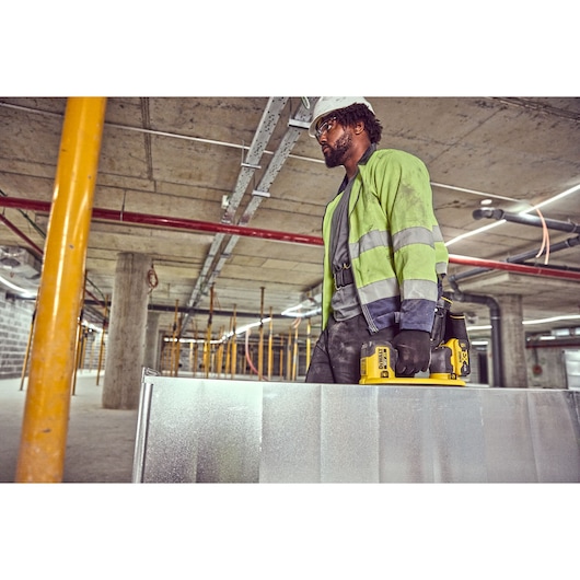 Construction worker carries metal duct framework using the Grabo 18V XR Suction Lifter