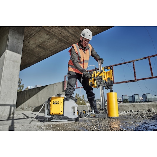 Construction worker using 18V XR Brushless water tank alongside Powershift core drill