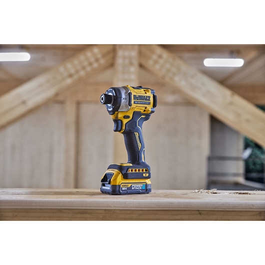 Angled view of 18V XR 4 Speed Premium Impact Driver with Powerstack battery standing on wooden beam
