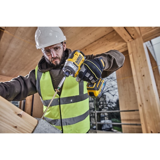 Construction worker uses 18V XR 4 Speed Premium Impact Driver to drive a bolt into a bracket on wood