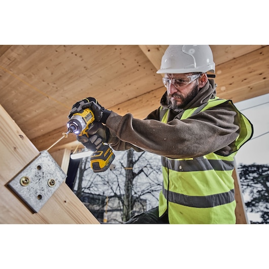 Construction worker uses 18V XR 4 Speed Premium Impact Driver to fix a bracket onto wood