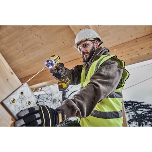 Construction worker uses 18V XR 4 Speed Premium Impact Driver to drive a long bolt into a bracket on wood