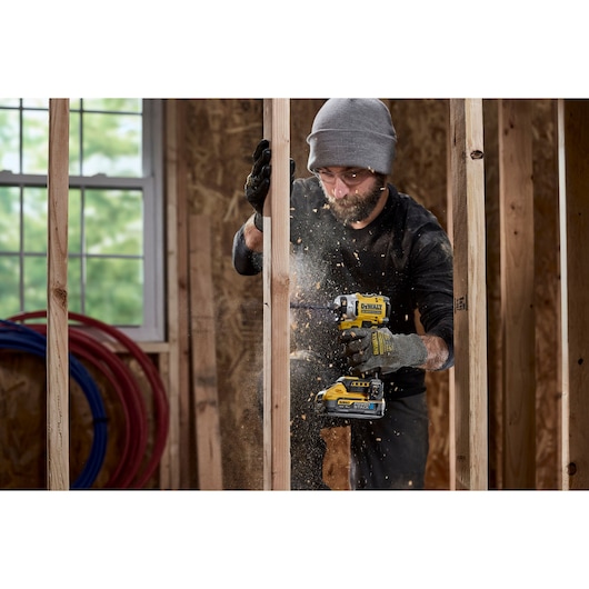 Construction worker uses 18V XR 4 Speed Premium Impact Driver to drill a hole into wooden stud wall