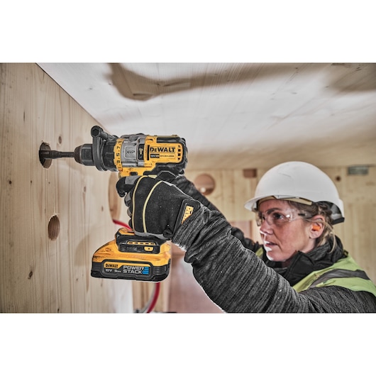 18V XR Brushless drill driver with Powerstack battery cutting hole into wooden wall