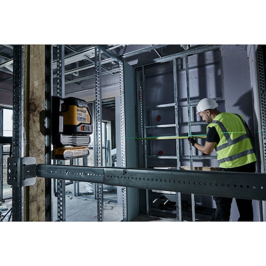 Green Cross Line Laser beaming on to metal work on a construction site. A workman is using the beam to measure