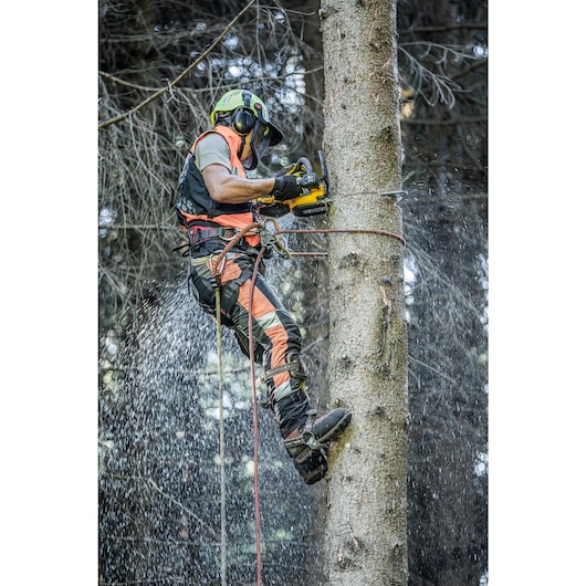 Arborist at height harnessed to to tree sawing with the DCMCST635 Top Handle Chainsaw