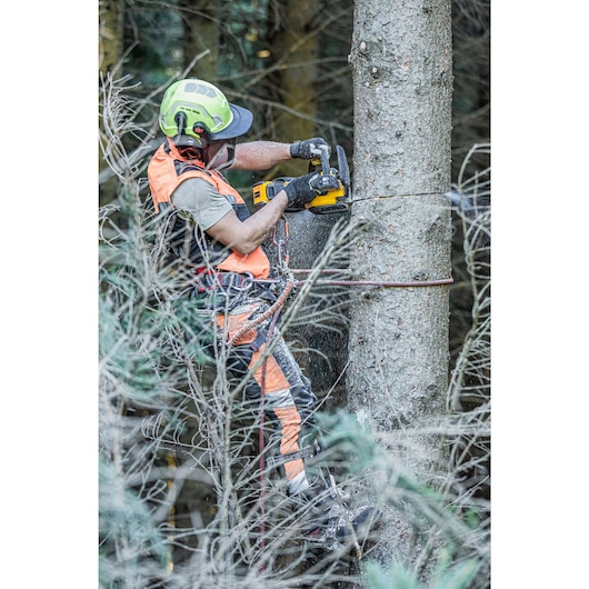 Arborist cutting through tree using the DCMCST635 Top Handle Chainsaw