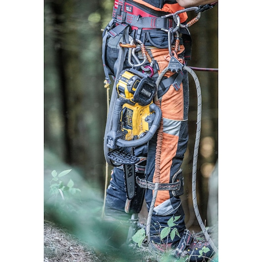 Arborist ground level with the DCMCST635 Top Handle Chainsaw with tether harnessed attached