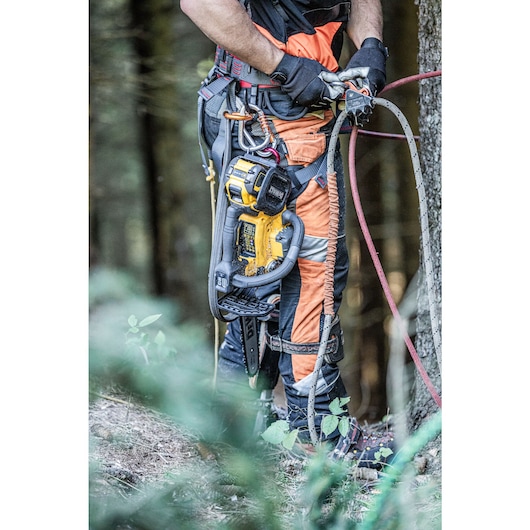 Arborist preparing to climb tree with the DCMCST635 Top Handle Chainsaw attached