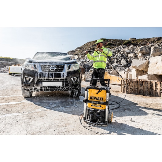 Worker cleaning a black truck with the Dewalt 2 x 18V Cordless Pressure Washer