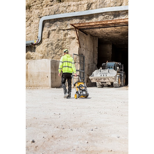 Worker pulling the Dewalt 2 x 18V Cordless Pressure Washer over rough ground