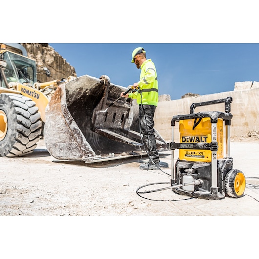 Worker cleaning a construction digger with the Dewalt 2 x 18V Cordless Pressure Washer