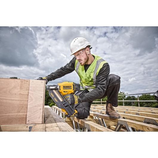 Worker on rooftop using DCN930 18V XR Brushless framing nailer to drive nails  into wood