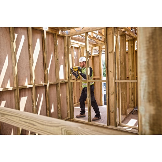 Worker using DCN930 18V XR Brushless framing nailer on a wooden frame on a construction site