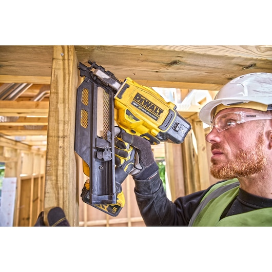 Construction worker using DCN930 18V XR Brushless framing nailer to drive nails into a wooden frame