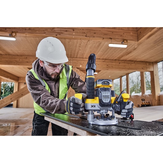 Construction worker using the 12mm plunge router on compact laminate holding moulded handles on site