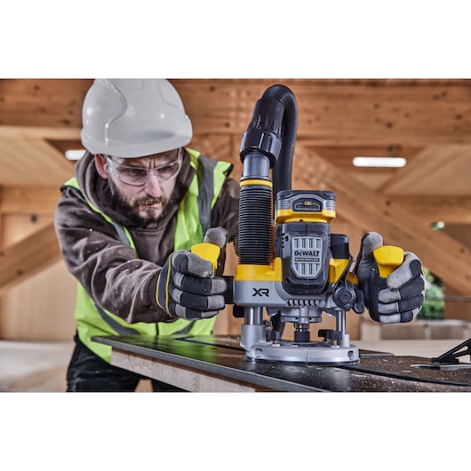 Construction worker using the 12mm plunge router on compact laminate holding moulded handles