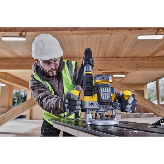 Construction worker using the 12mm plunge router on compact laminate on site