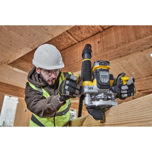 Close up of worker using the 12mm plunge router with dust port and edge attachment on timber