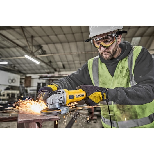 Worker uses DWE4036 angle grinder on metal, producing flying sparks