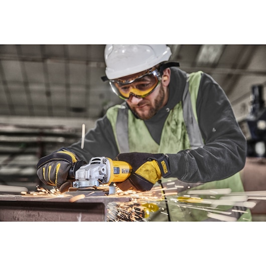 Worker uses DWE4036 angle grinder on metal, producing orange flying sparks