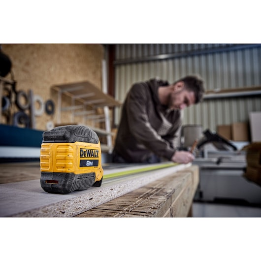 Man measuring with 8 meter compact tape, product focus