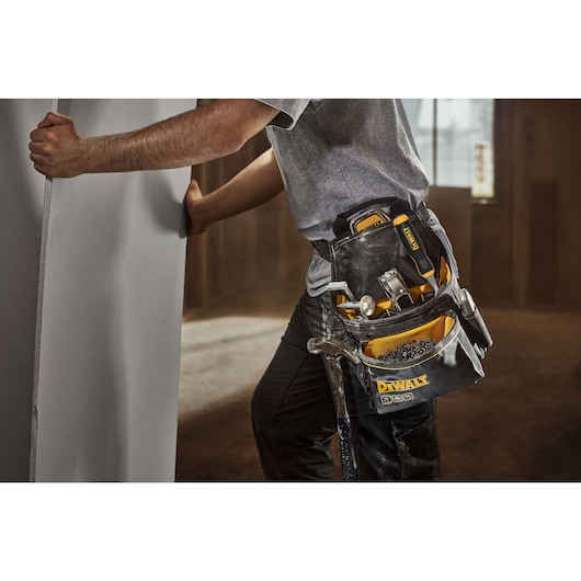 Person wearing the Dewalt Professional tool pouch. The pockets are filled with nails and hand tools.