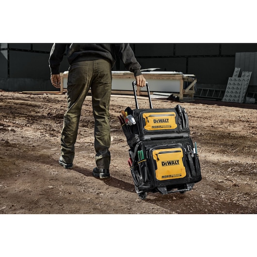 Construction worker rolls stacked Tool Bags across a construction site