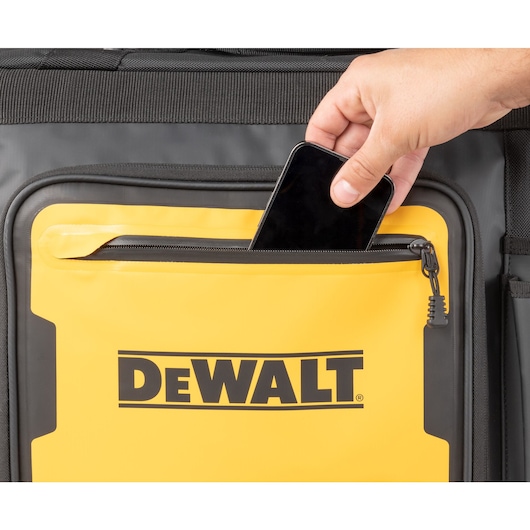 Close up of a mobile phone being slotted into the front pocket on the Dewalt 18" Pro Rolling Tool Bag"